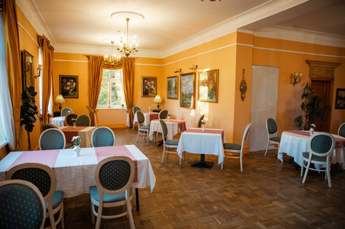 Mārcienas Muižas restorāna elegantais interjers ar vēsturisku noskaņu un sveču gaismām