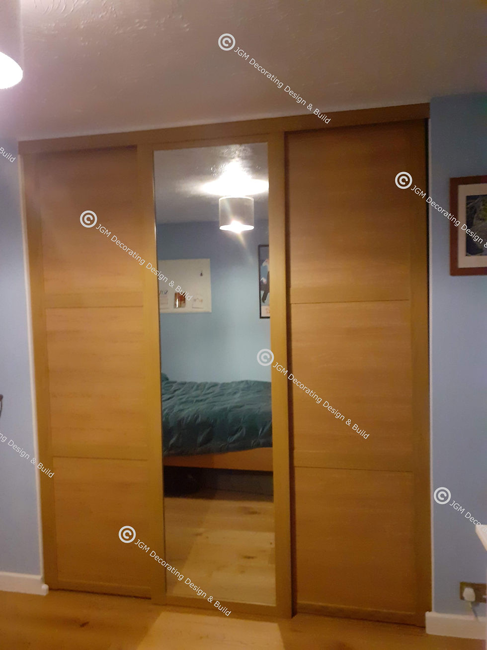 JGM Decorating Design & Build. Bespoke sliding doors in oak finish with central mirror