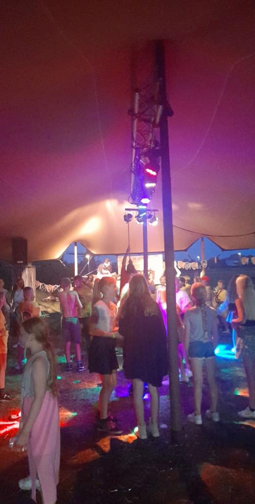 Dansende mensen in een feesttent met roze licht