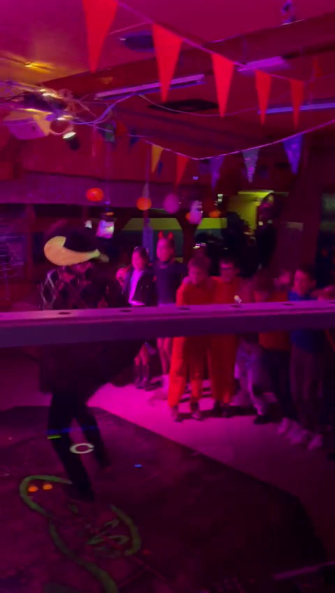 Dansende mensen in een zaal met vlaggetjes en roze licht