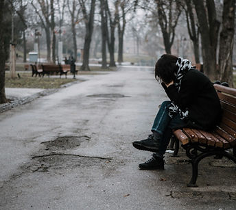 Person with head in hands sitting on a bench