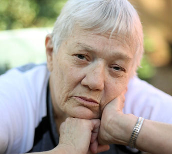 Older person with hands on chin leaning forward, looking down or concerned