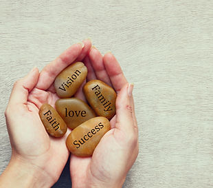 Systemic Coaching: Hands holding stones with terms like vision, love & success – symbol for personal values and clarity