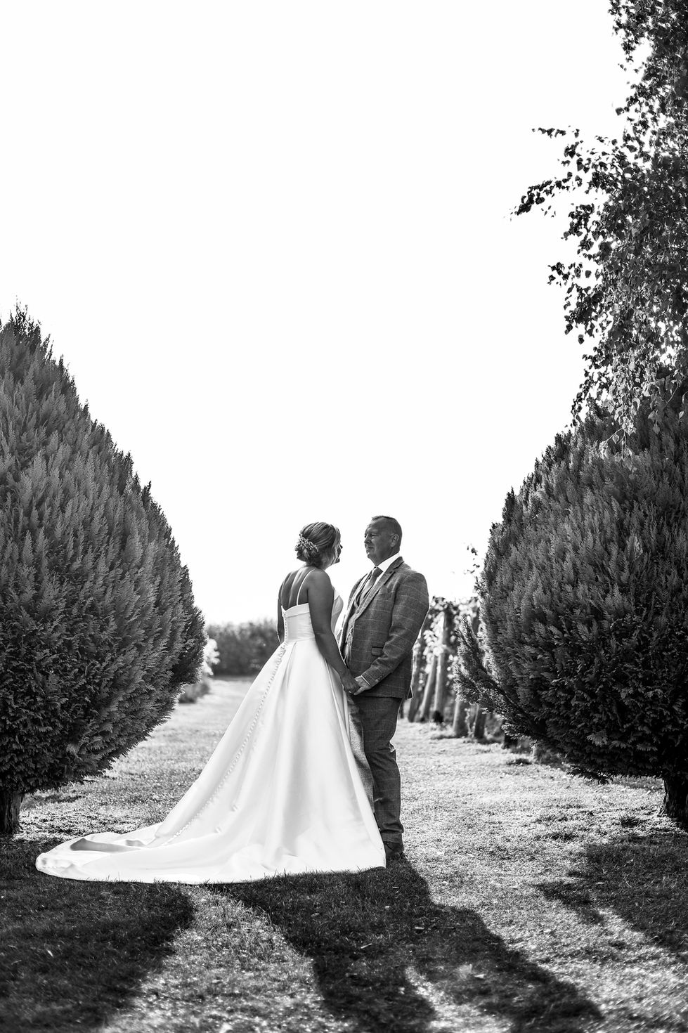 Bride and Groom face each other in the middle of trees in Northampton Vineyard