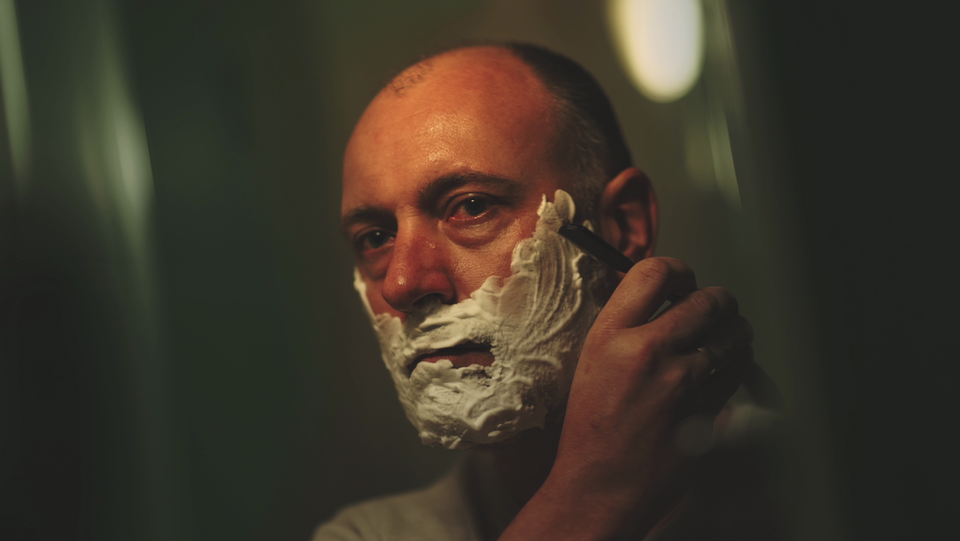 Dean Kilbey with shaving foam on his face holding a razor