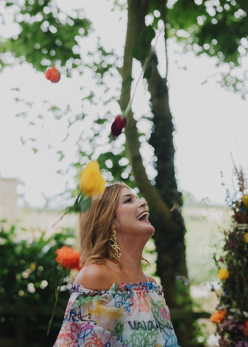 Joyful bride dancing amidst vibrant flowers, her radiant smile captured beautifully by photographer Holly Cook.