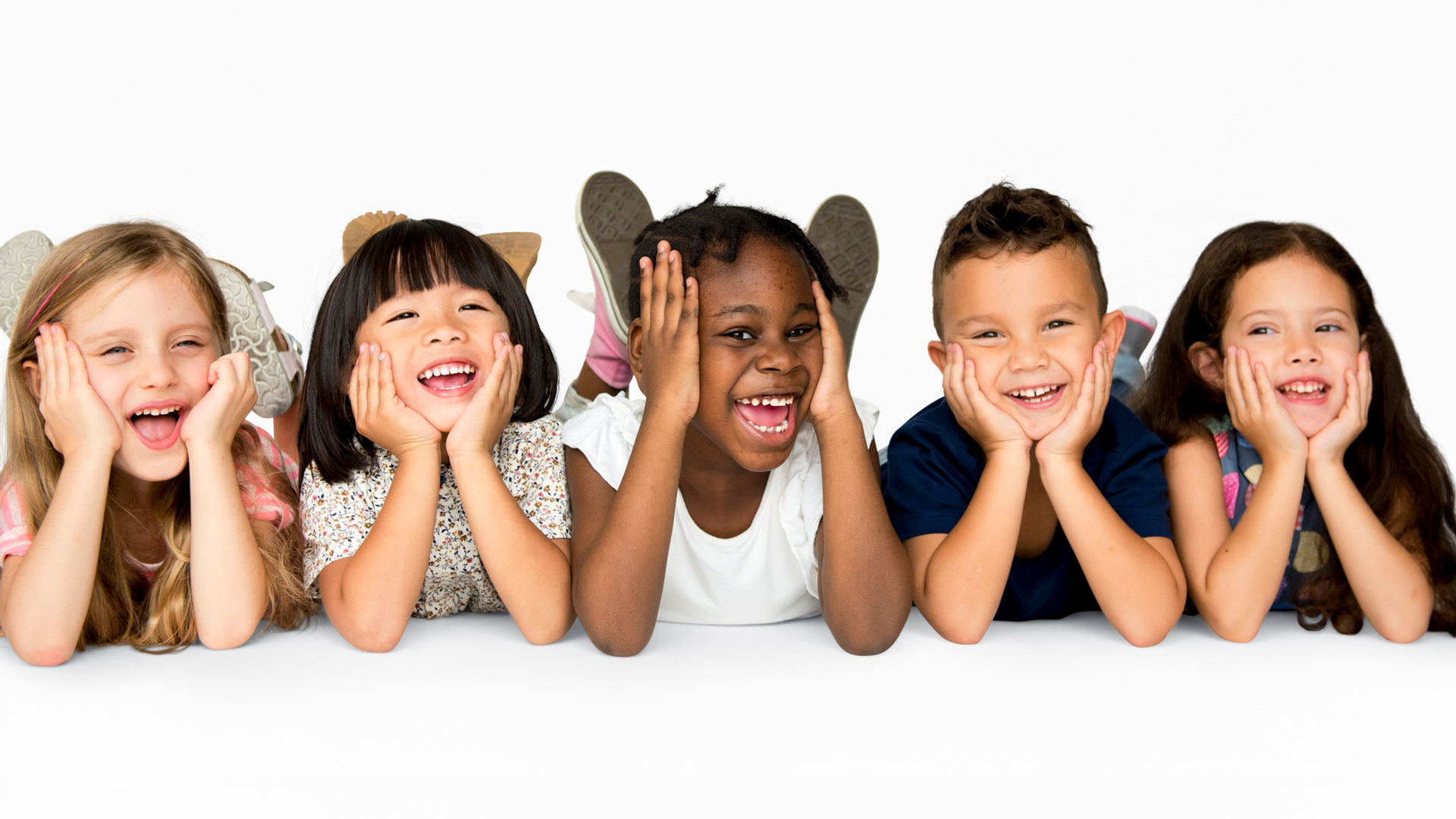 Row of kids laying on the floor smiling happily while sharing the same pose