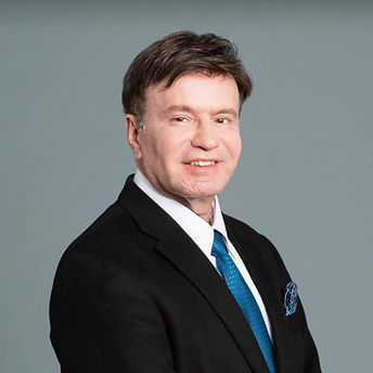 Professional headshot of Dr. Jerry Shapiro, Advisory Board Member, in a black suit with a blue tie, against a grey background