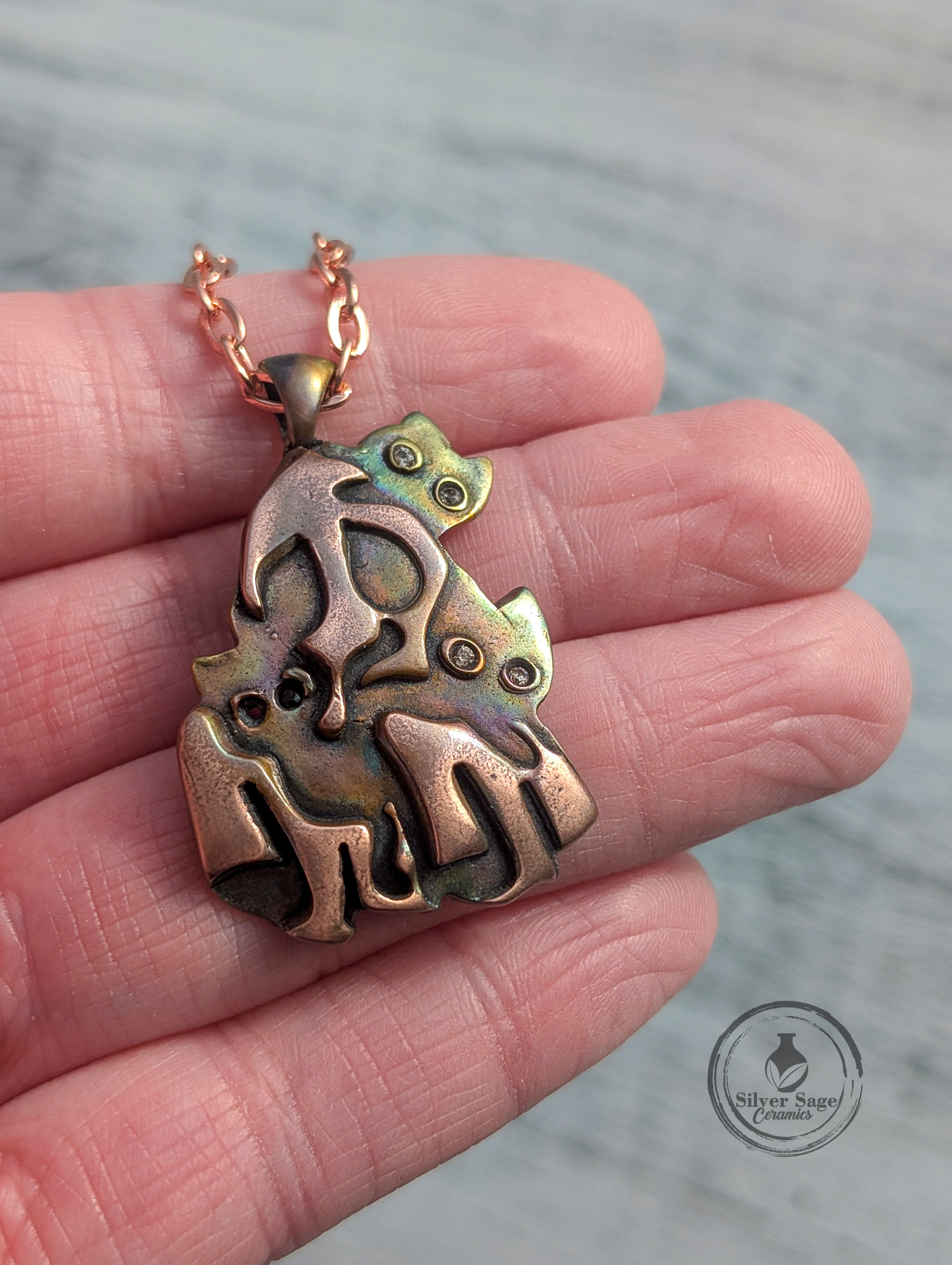 Flame painted copper ghost pendant holding a cat with CZ gemstone eyes