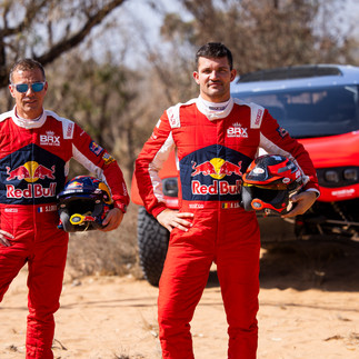 Sébastien Loeb and Fabian Lurquin stand in the desert in front of their BRX Prodrive Hunter