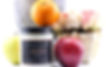 fruit nectar glass container next to apple orange and roses and vase
