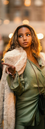 Woman in green dress and faux fur coat on city street. Photography by Rafael Mercedes.