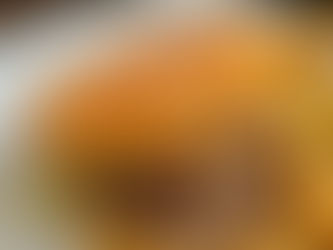 A sesame seed burger with lettuce and sauce on a white plate, served with golden fries. Warm lighting and a rustic background set the mood