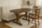 Lifestyle kitchen nook with banquette seating styled around cherry oval trestle dining table in espresso finish,