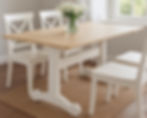 Brigid Three Trestle Dining Table styled in a bright dining room with white chairs and a vase of fresh daisies on top.