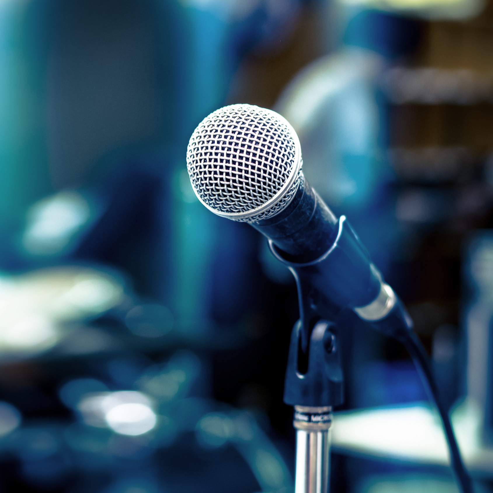 microphone stand with a microphone in it and a drum set in the background
