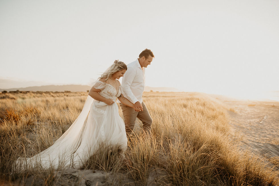 Bride and Groom walking hand in hand along Ohope Beach during their bridal portraits with Bay Of Plenty Wedding photographer RM Photo
