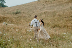 Couple walking through farmland during wedding portraits in native bush on private property near Whakatane NZ