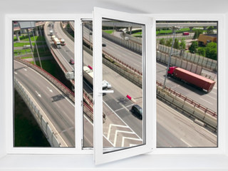 Image shows an open window with a noisy busy road outside. Clear Acoustic Design provide a range of road noise surveys to reduce noise levels from all sources of road traffic.