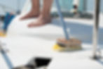 Man washing white boat with brush and pressure water system at pier. Yacht maintenance con