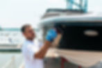 Boat maintenance - Man with orbital polisher polishing boat in marina..jpg