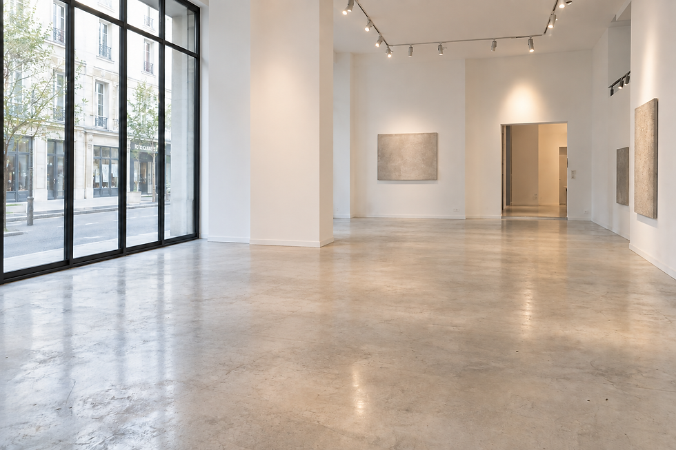 Galerie d'art lumineuse avec sol en béton poli et tableaux.
