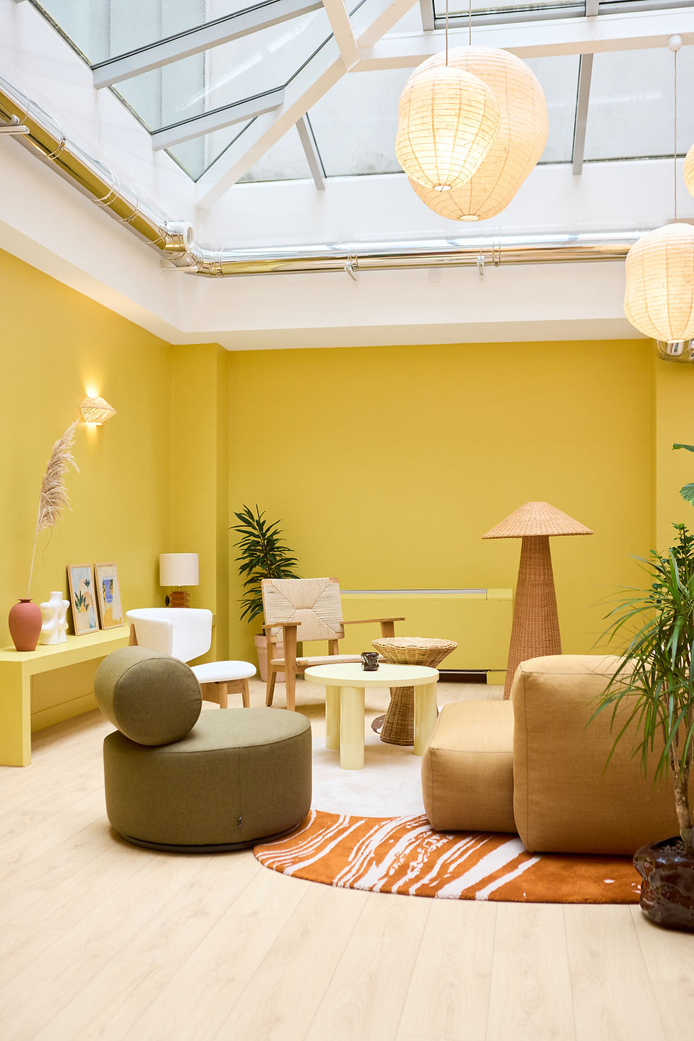 Salon chaleureux aux nuances de jaune et d'ocre, décoré de suspensions en papier et de matières naturelles