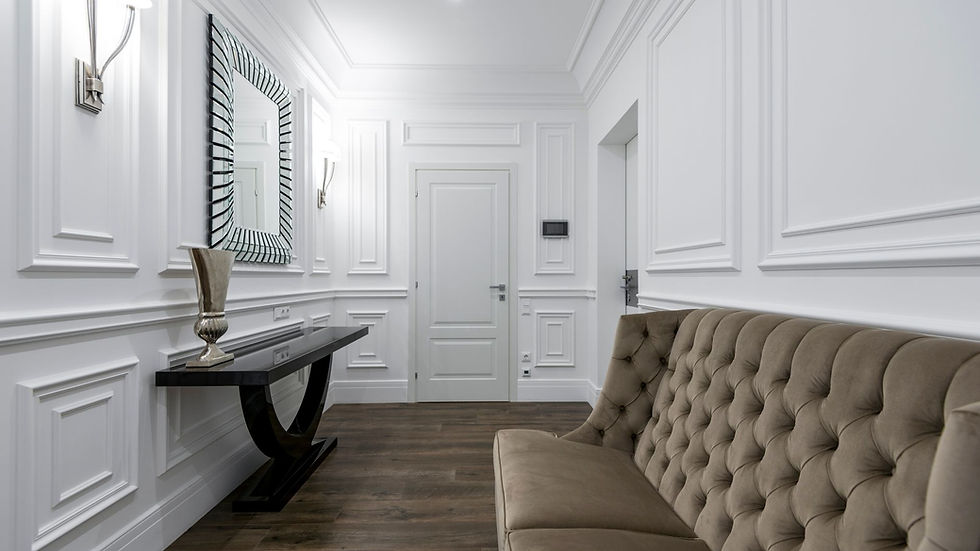 Luxurious white interior featuring a modern tufted sofa and classic wall paneling.