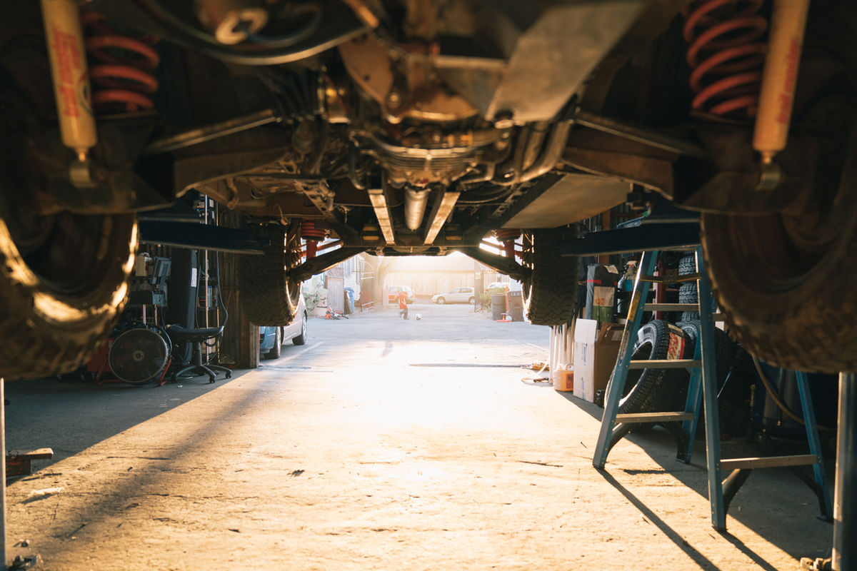 Looking across a workshop from under a car on a lift