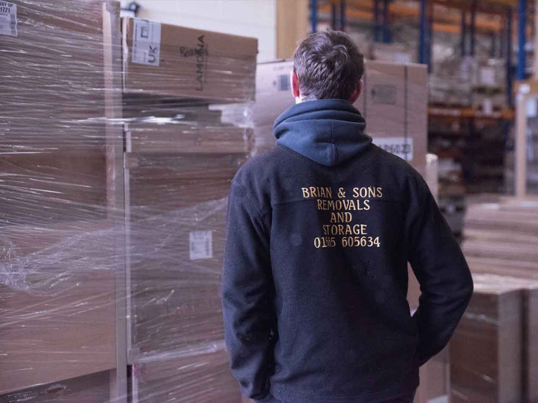 A Brian & Sons team member inside the store, between shrink-wrapped goods and racking