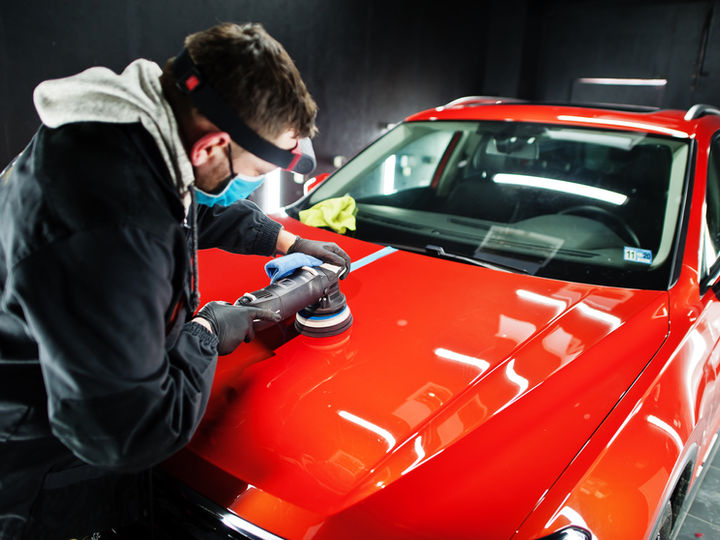 Detailer machine polishing a car in a workshop