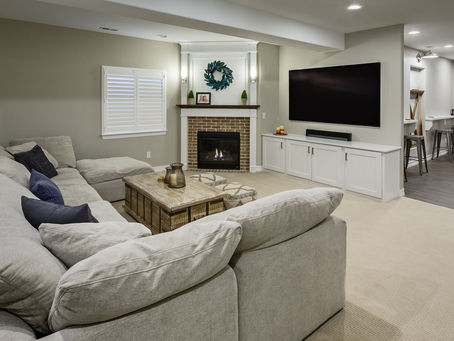 Cozy living room with a gray sectional, wood table, and large TV. Brick fireplace with decor and candles. Neutral tones create a warm ambience. In Cache Valley Salt to Summit