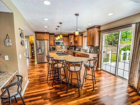 Spacious modern kitchen remodel in Logan, Utah featuring hardwood floors, granite countertops, and custom cabinetry with pendant lighting, completed by Salt to Summit Construction & Renovation.