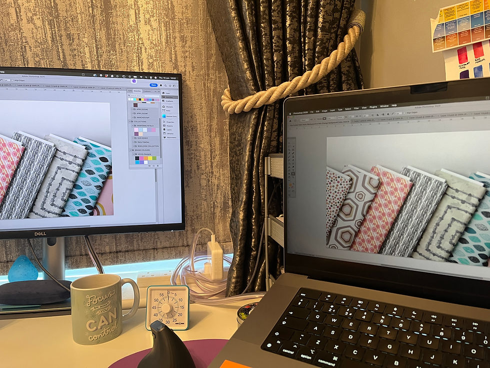 Dual computer screens showing textile mockups in Adobe Photoshop, featuring geometric and abstract surface pattern designs in a home studio workspace.