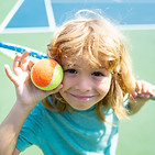 Child playing tennis on outdoor court. Little girl with tennis racket and ball in sport cl