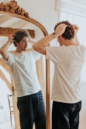 Photo du coiffeur de la mariée lui pose le voile pendant les préparatifs au Domaine WE - Côte d'Opale