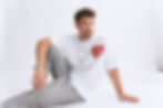 Thumbnail: Man in white T-shirt with heart design sits on floor