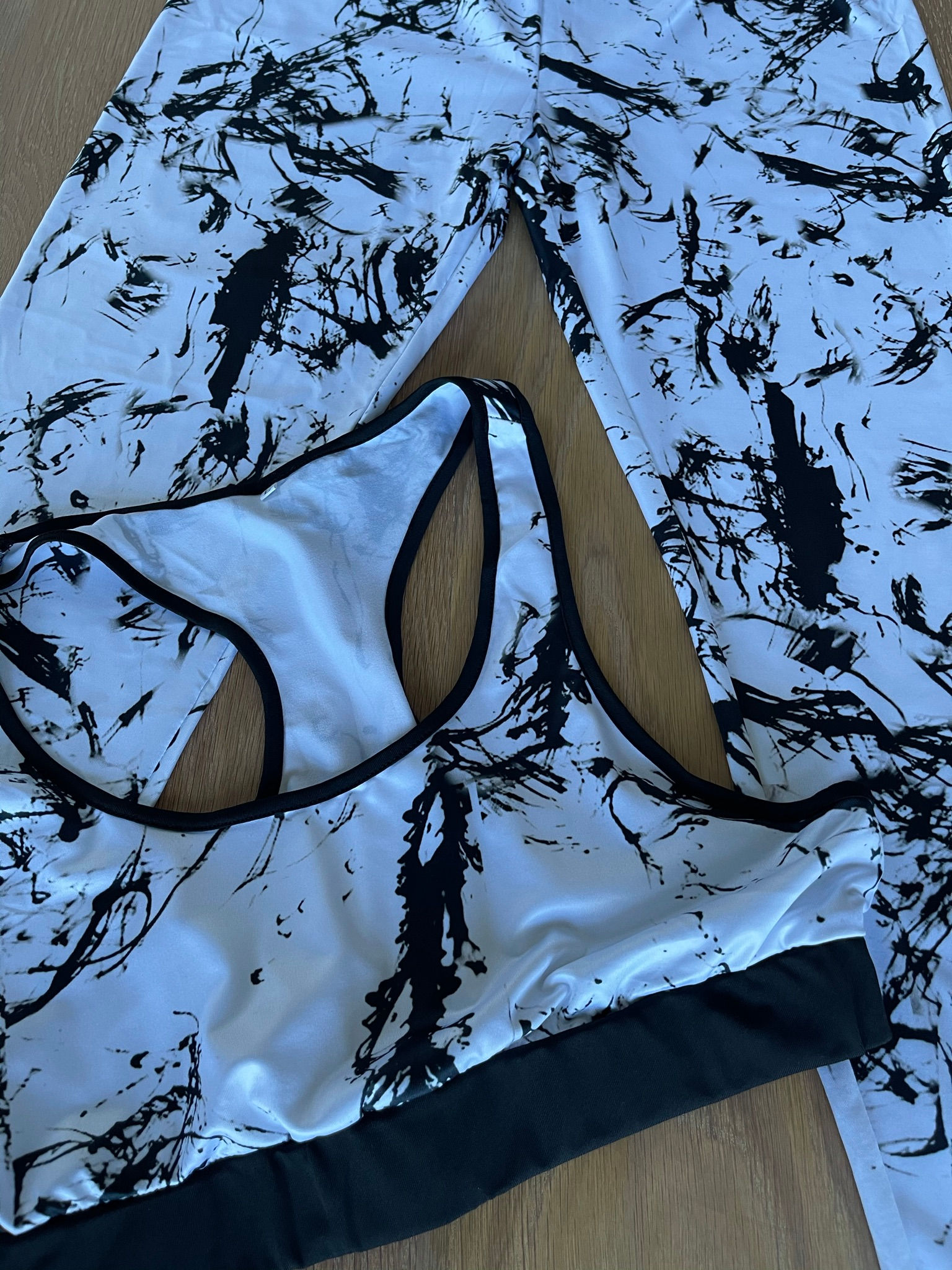 Flat lay on wood - activewear set with abstract splatter print leggings and matching sports bra