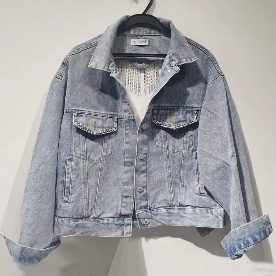 Minijatura: Light blue denim jacket hanging on a hanger against white background.