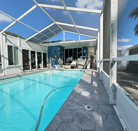 Before photo of a pool cage with mold on the frame, dirty screens, and a weathered pool deck.