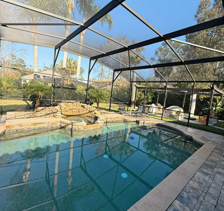 After photo of a restored pool cage with a clean black frame and clear screens surrounding the pool.