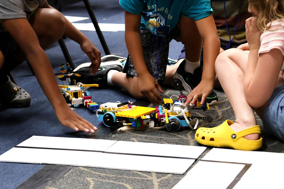 The hands and feet of three children having a LEGO robot battle.