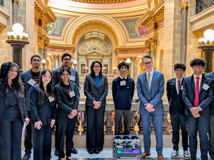 Group of Wisconsin robotics students in business attire posing with their robot and representatives in the Wisconsin State Capitol.