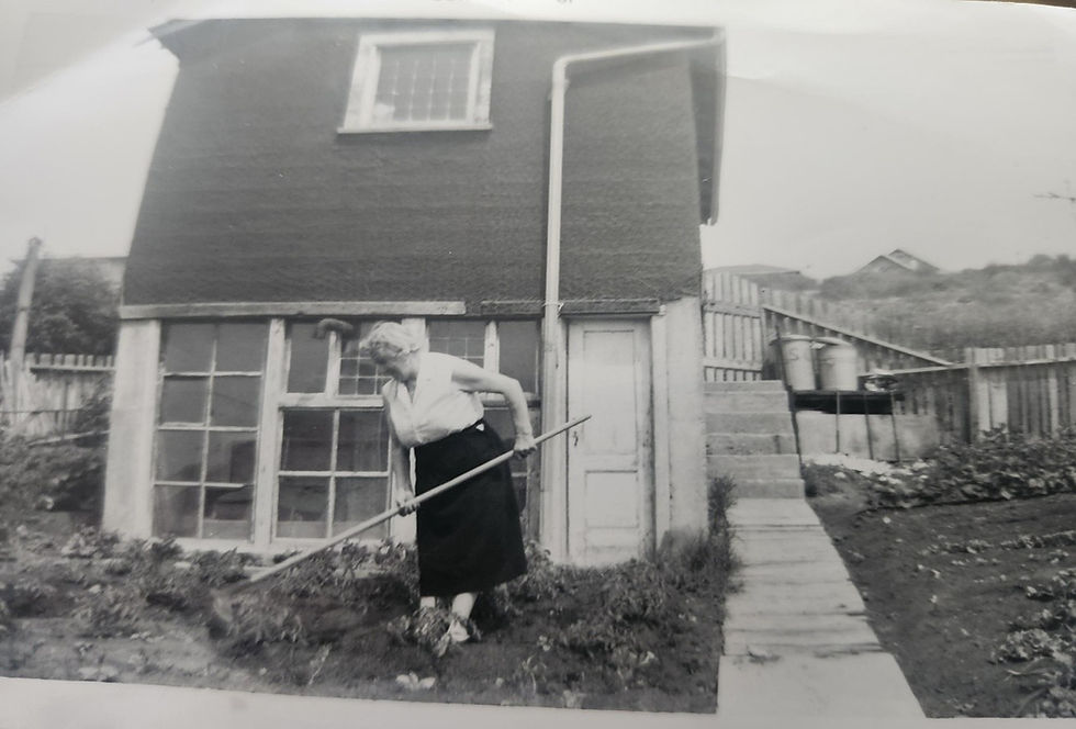 Isa Buccini raking a garden by a small shed