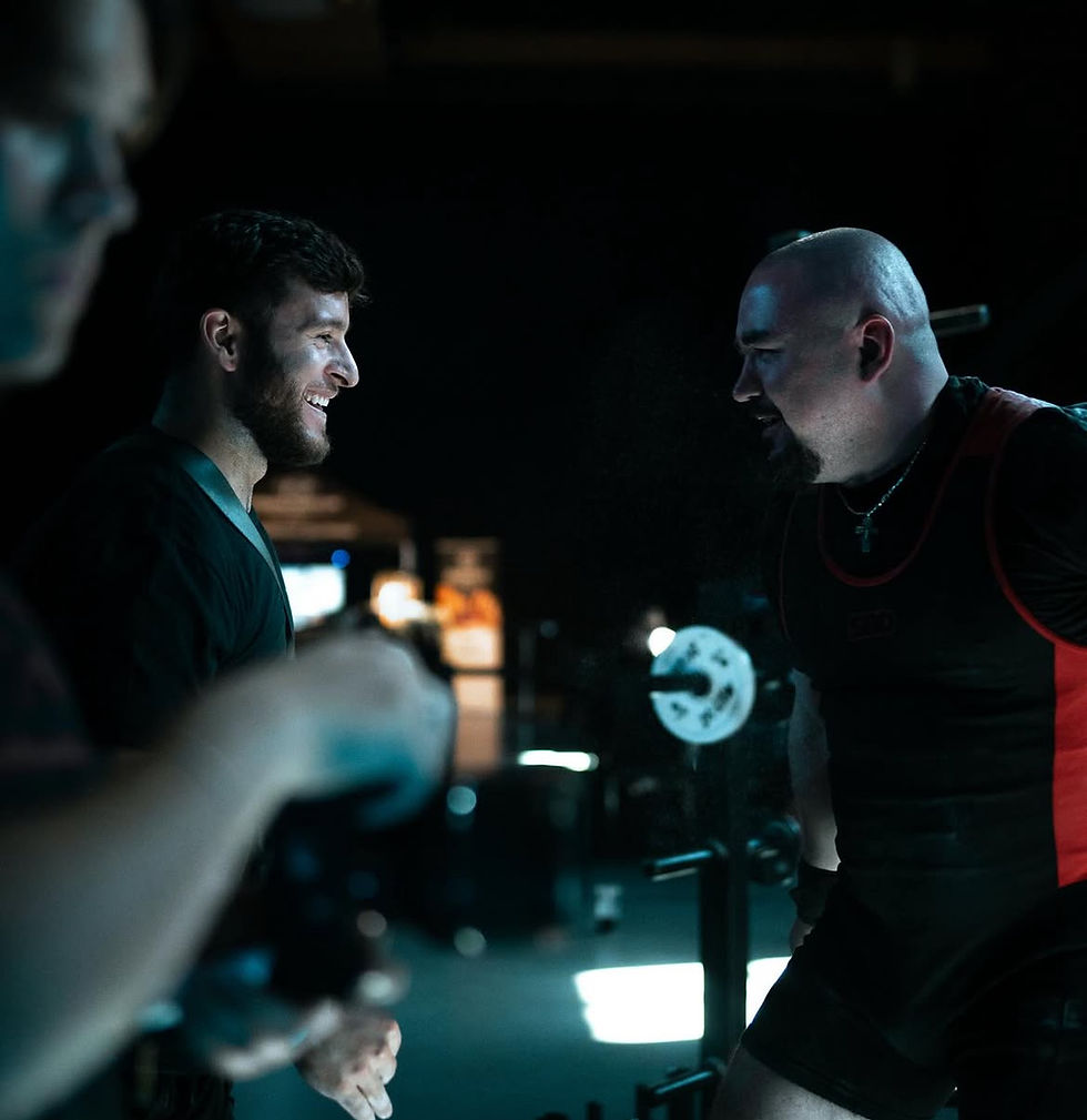 Deux hommes sourient et se saluent, dans une salle sombre, My Site 2.