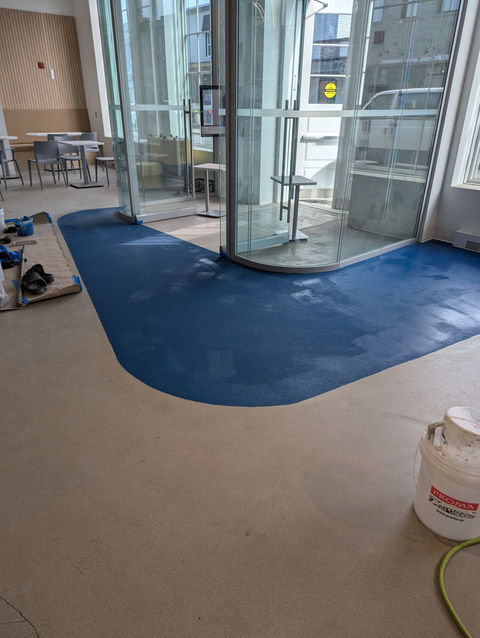 Sol bleu fraîchement posé dans un espace moderne avec cloisons vitrées.