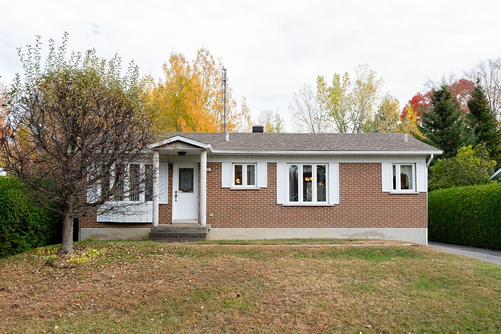 Maison en briques rouges avec porte blanche et fenêtres, paysage automnal en arrière-plan.