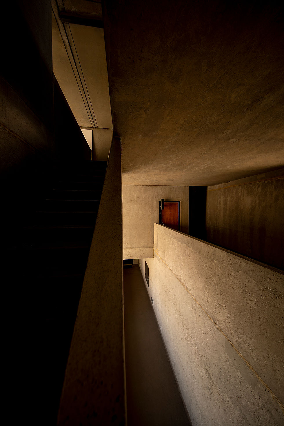 Couloir en béton, contrastes d'ombre et lumière.