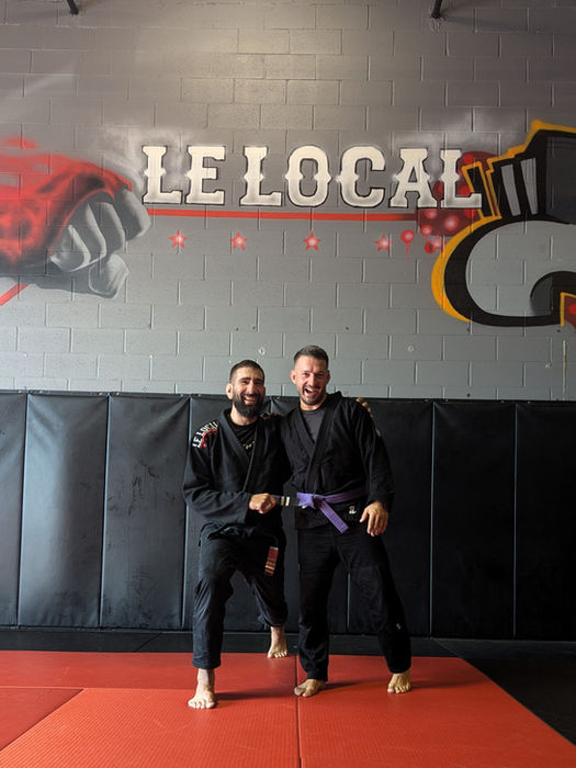 Deux hommes en kimono, un à ceinture violette, au gym