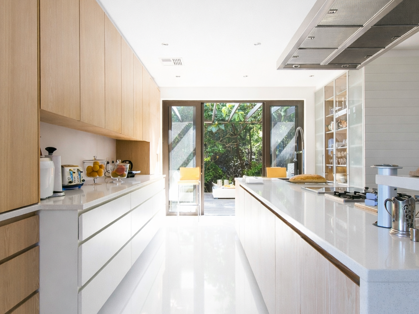 Cuisine moderne lumineuse, armoires en bois clair, îlot blanc, vue jardin.